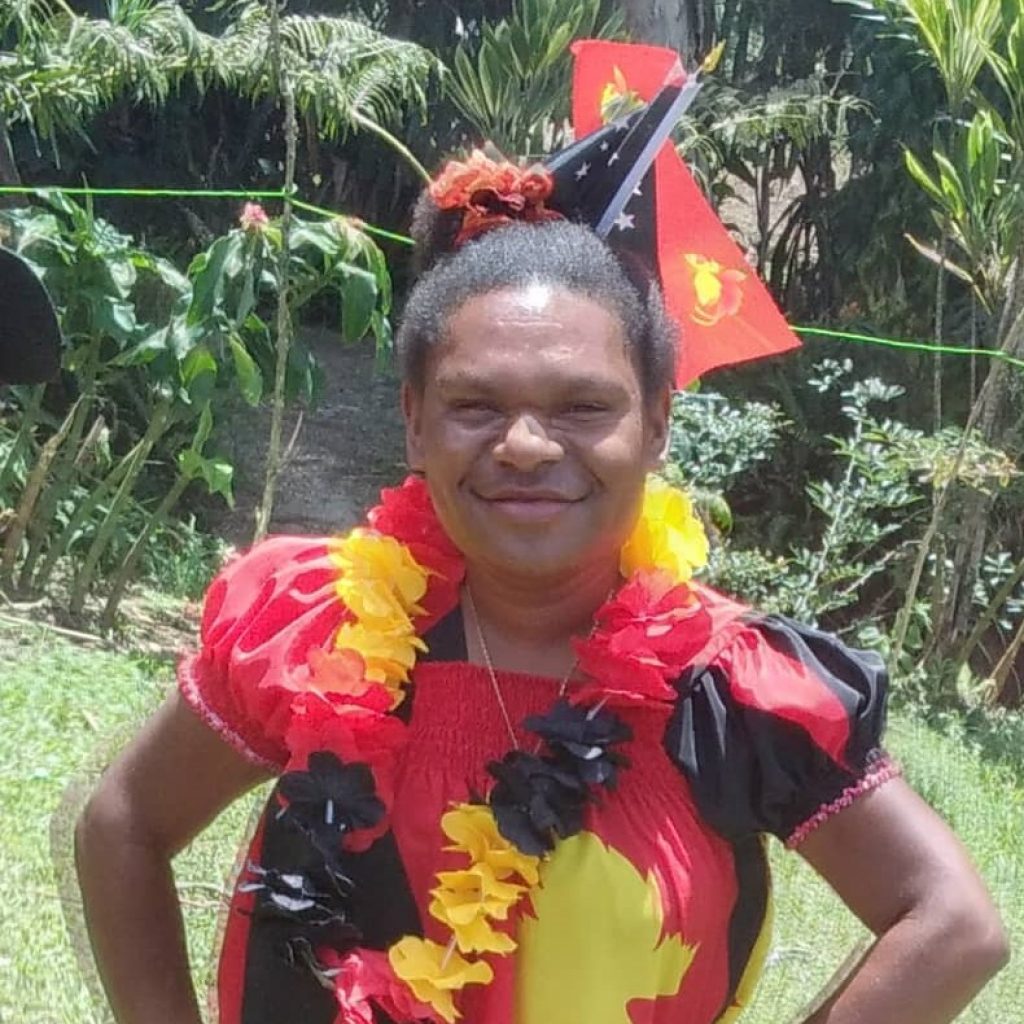 A young woman smilies with Papua New Guinea flags in the background