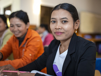 A woman sitting in a training session, she is smiling at the camera