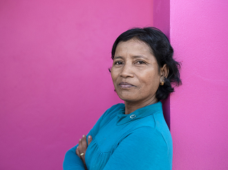 A woman stands with her arms crossed, she is looking into the camera