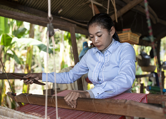 A woman is working on a weaving loom