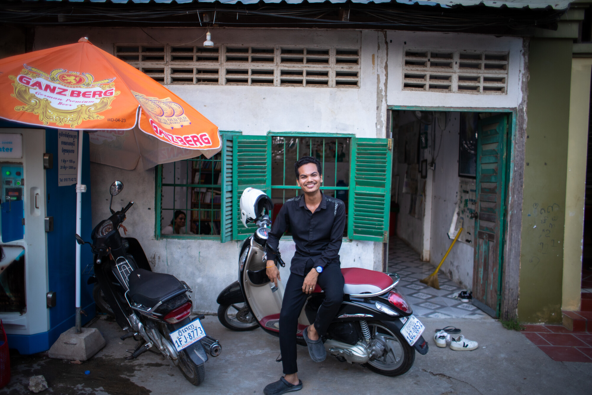 Chorn Phorn, a key organiser at WIC, is posing outside of one of WIC's drop-in centres in Phnom Penh. He is leaning against a motorcyle.