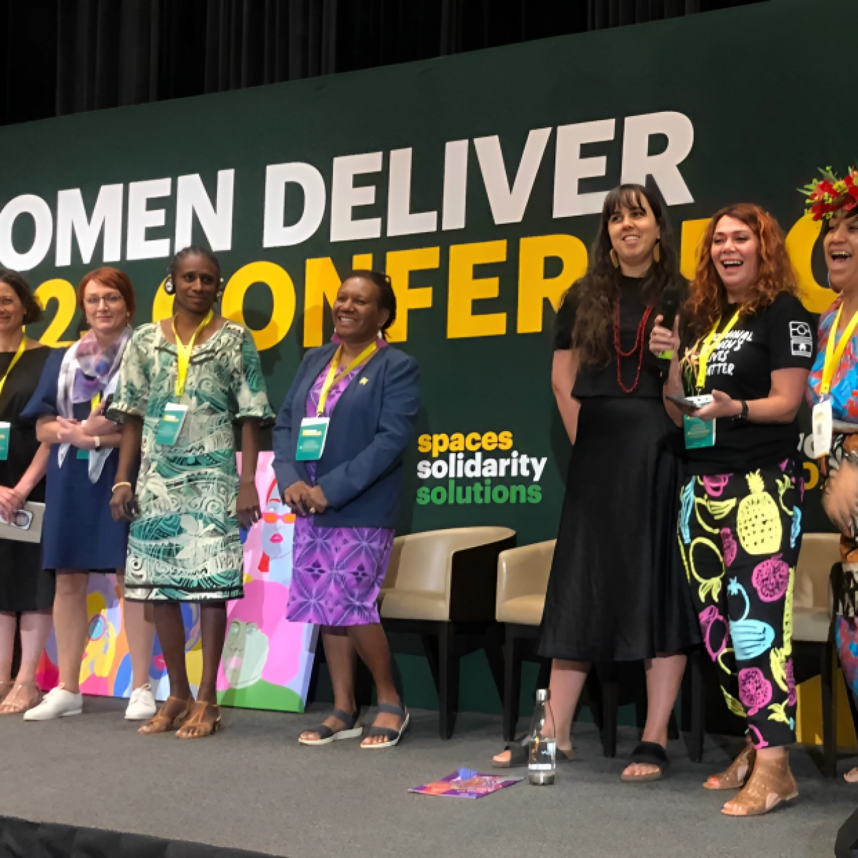 A group of people from around the world, including the Oceanic Pacific post for photos on a stage