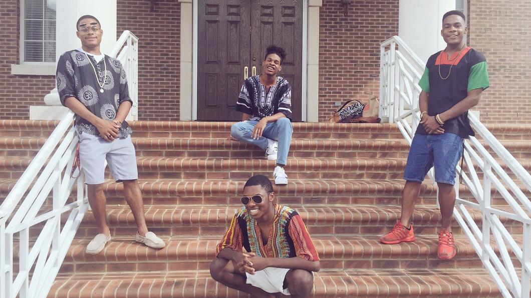 Four men wearing Dashikis in front of a University building. Photo: Complex