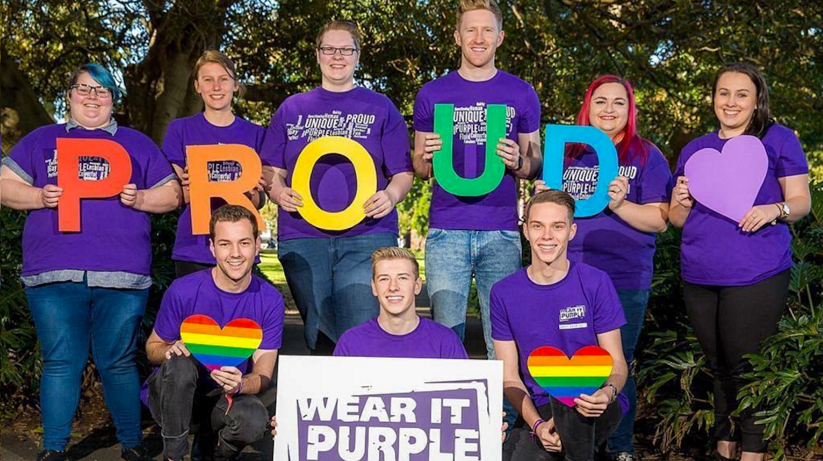 Image of young people wearing purple and a sign reading: "proud"